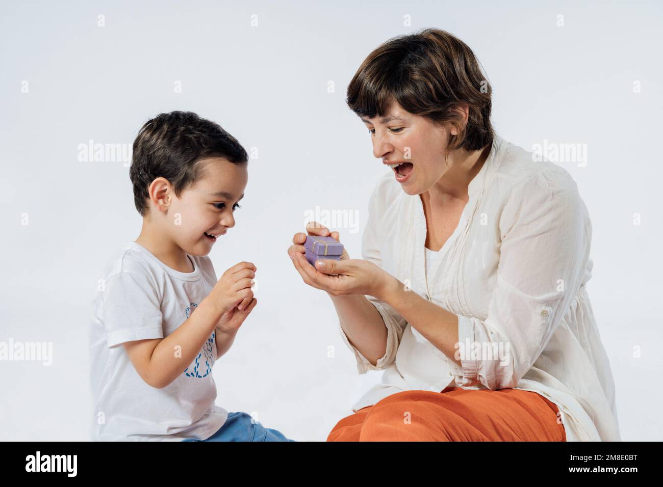 Happy mother's day! Son congratulating his mom and giving her a gift. Studio portrait on white background Stock Photo