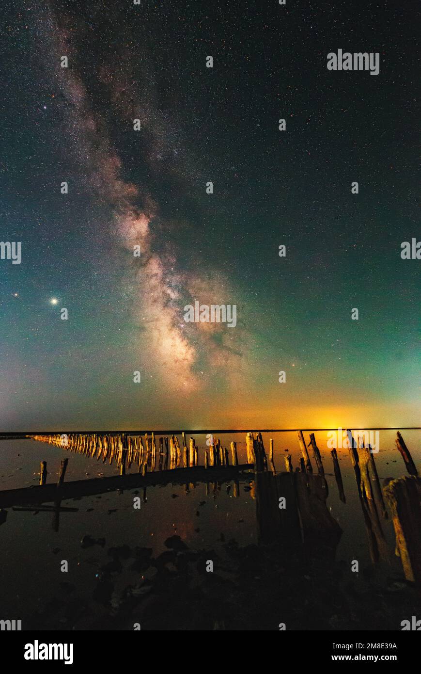 Bright night landscape with Milky Way galaxy stripe and Jupiter over the salt lake in Henichesk, Ukraine. Atmospheric green air glow effect Stock Photo