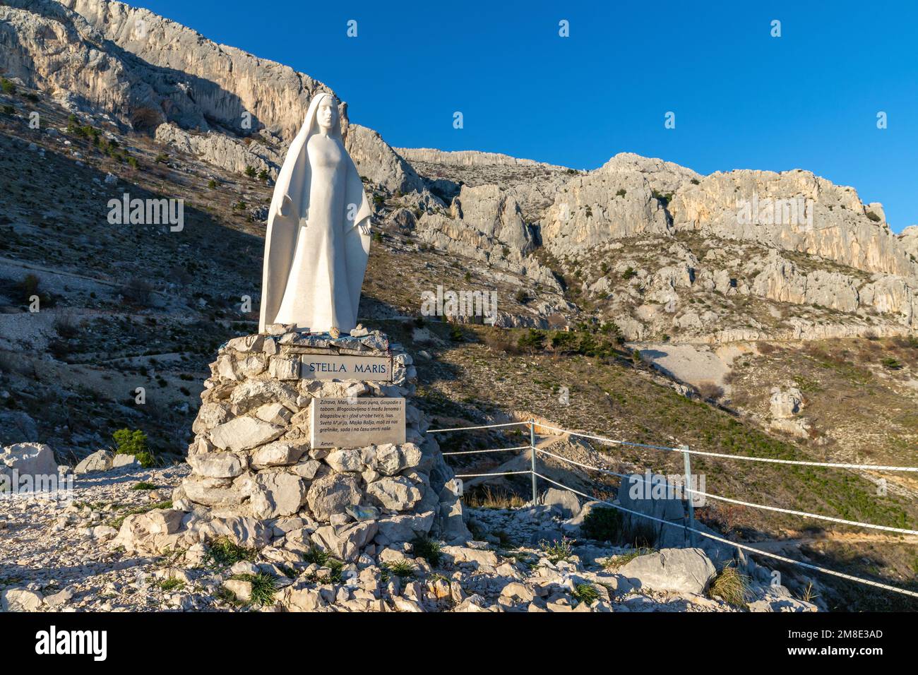 Stella Maris viewpoint and sculpture. Girl  prays near the Stella Maris (The Star of the Sea). Jesus' mother sculpture above the sea in Croatia. Stock Photo