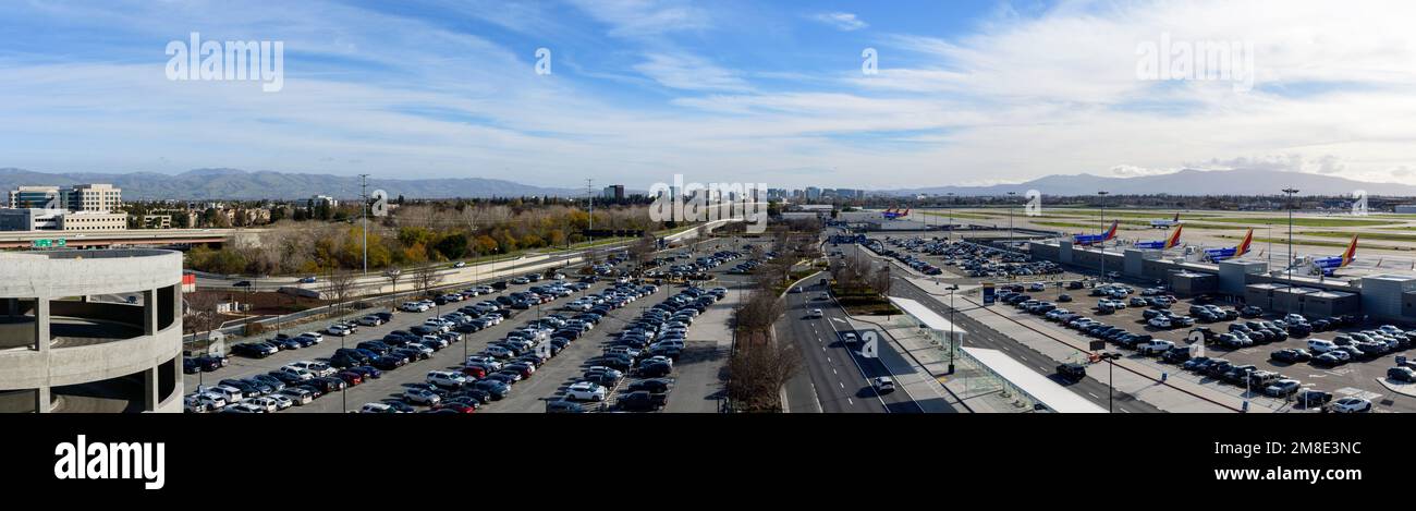 Aerial panoramic view of car parking lot and airfield of San Jose Mineta International Airport toward city downtown. Southwest Airlines planes parked Stock Photo