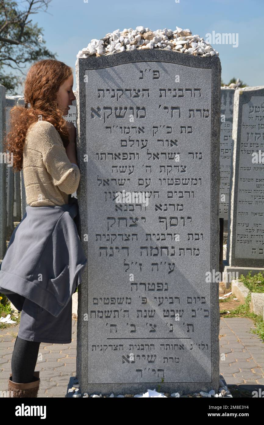 An orthodox Jewish young lady says a  personal prayer at te headstone of Chaya Mushka Schneerson, the wife of the Lubavitcher Rebbe. In Queens, NYC. Stock Photo