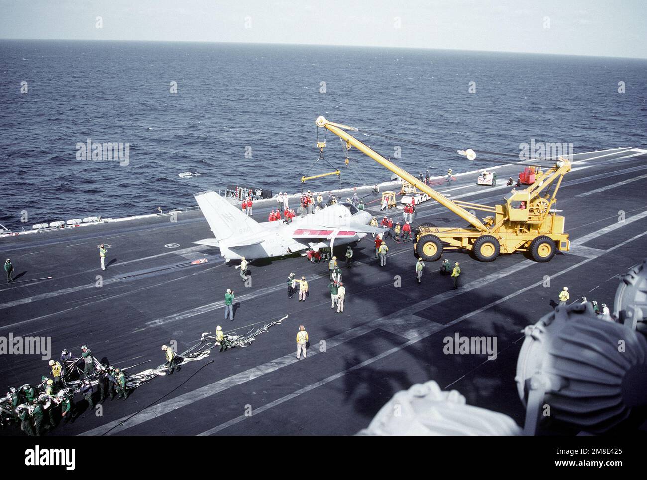 As flight deck crewmen haul away the crash barricade the crash crane