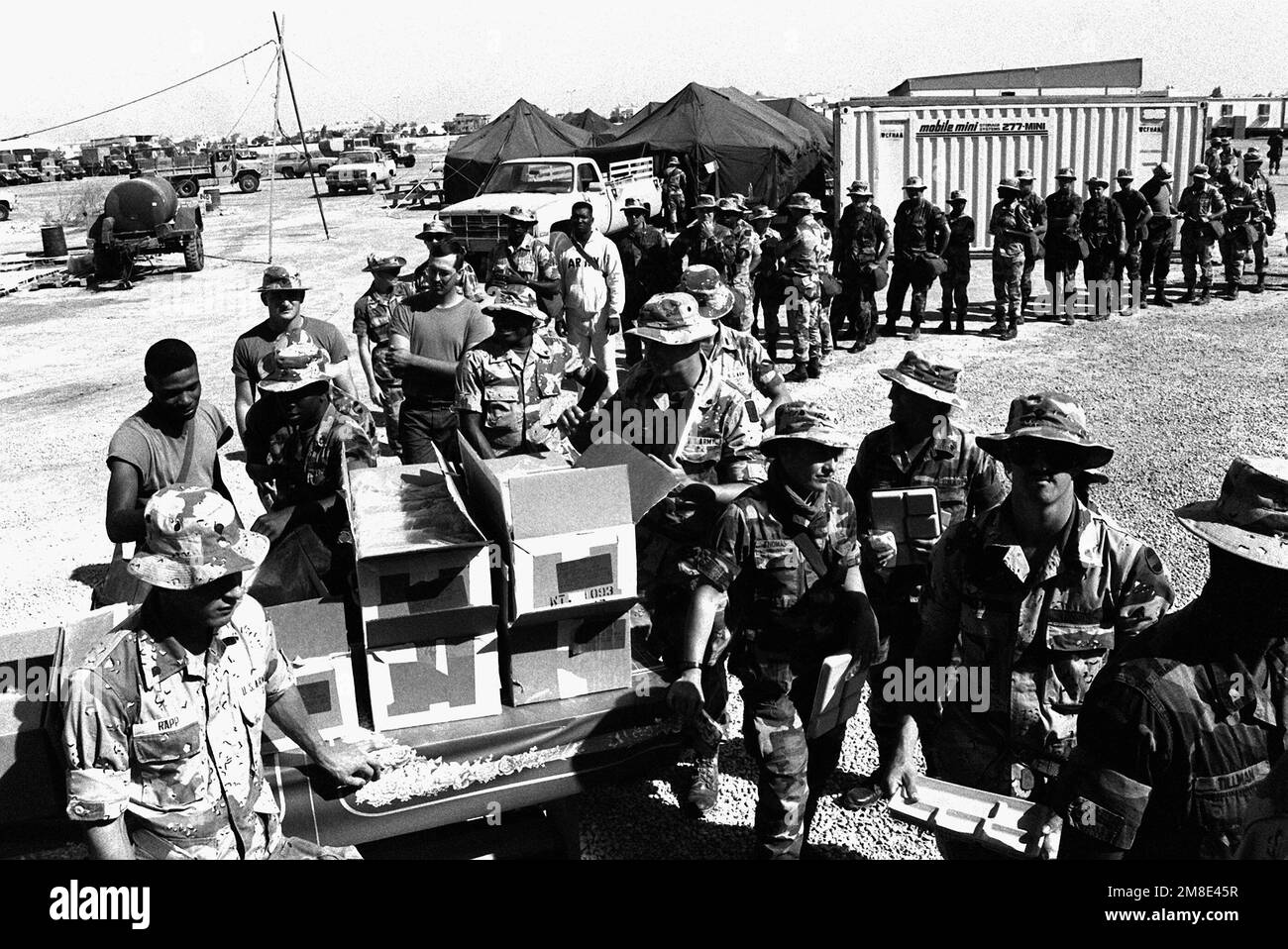 Soldiers of the 11th Signal Brigade and the 304th Signal Brigade line up to receive their noon meal of T-rations at Camp Messenger during Operation Desert Shield. Subject Operation/Series: DESERT SHIELD Base: Dhahran Country: Saudi Arabia (SAU) Stock Photo