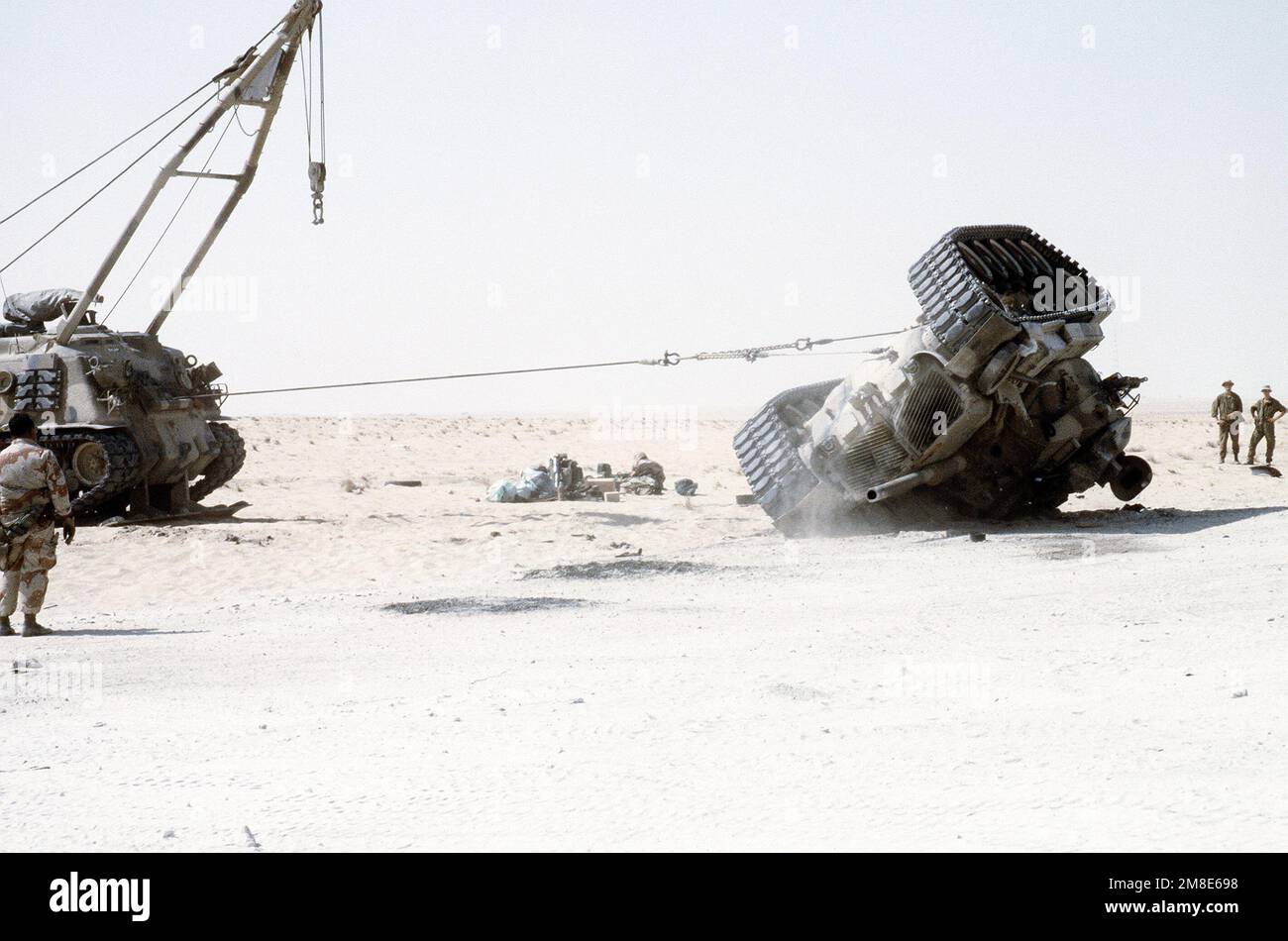 A Marine watches as an M-88A1 armored recovery vehicle uprights an ...