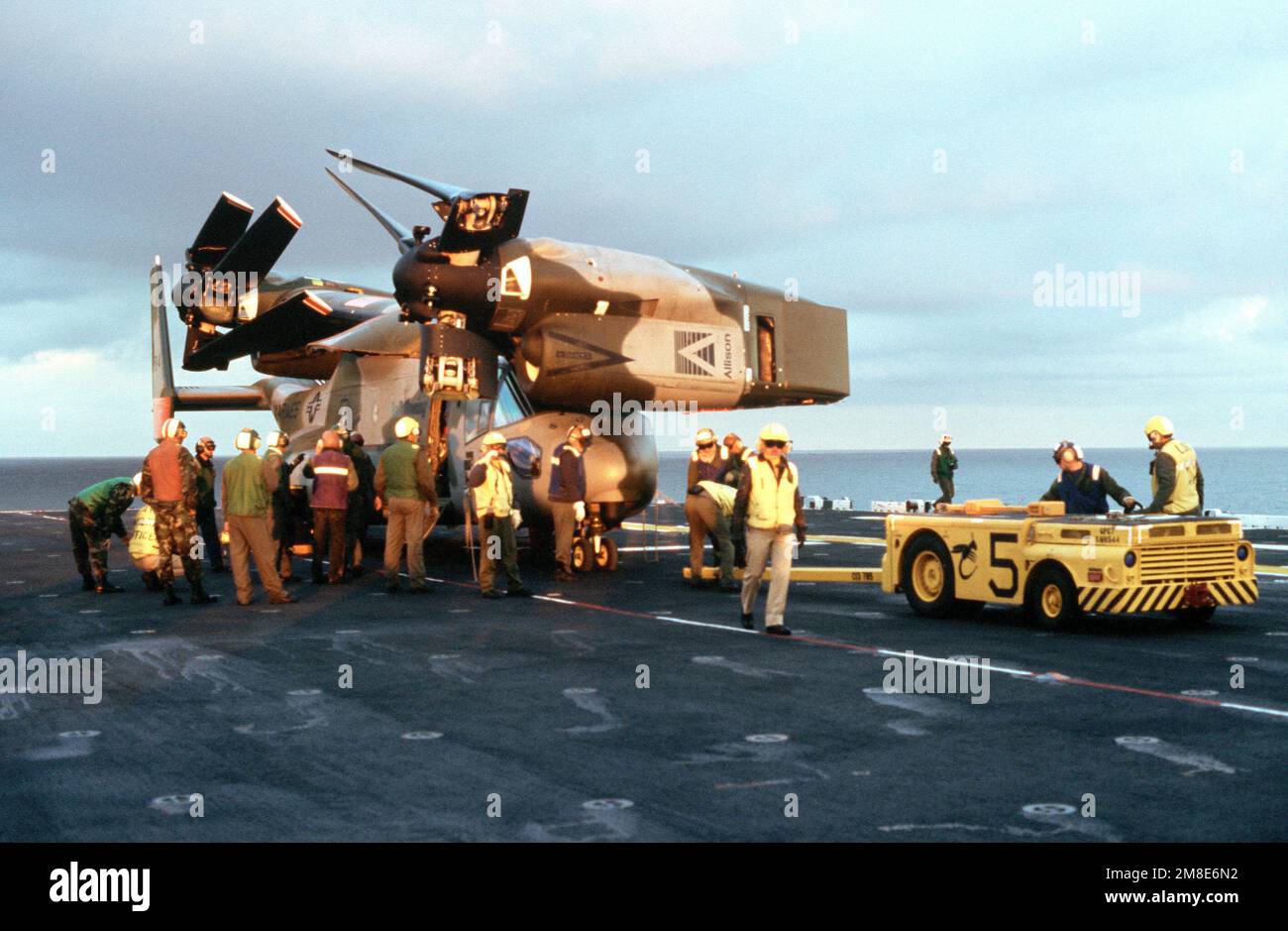 An MD-3A tow tractor backs into position as personnel crowd around a V ...