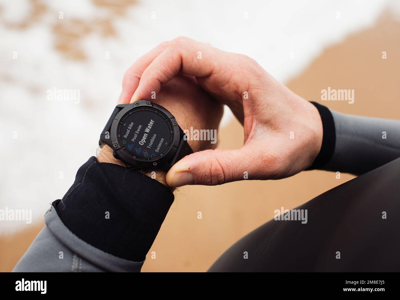 Man holding his sports watch ready for an open water swim Stock Photo