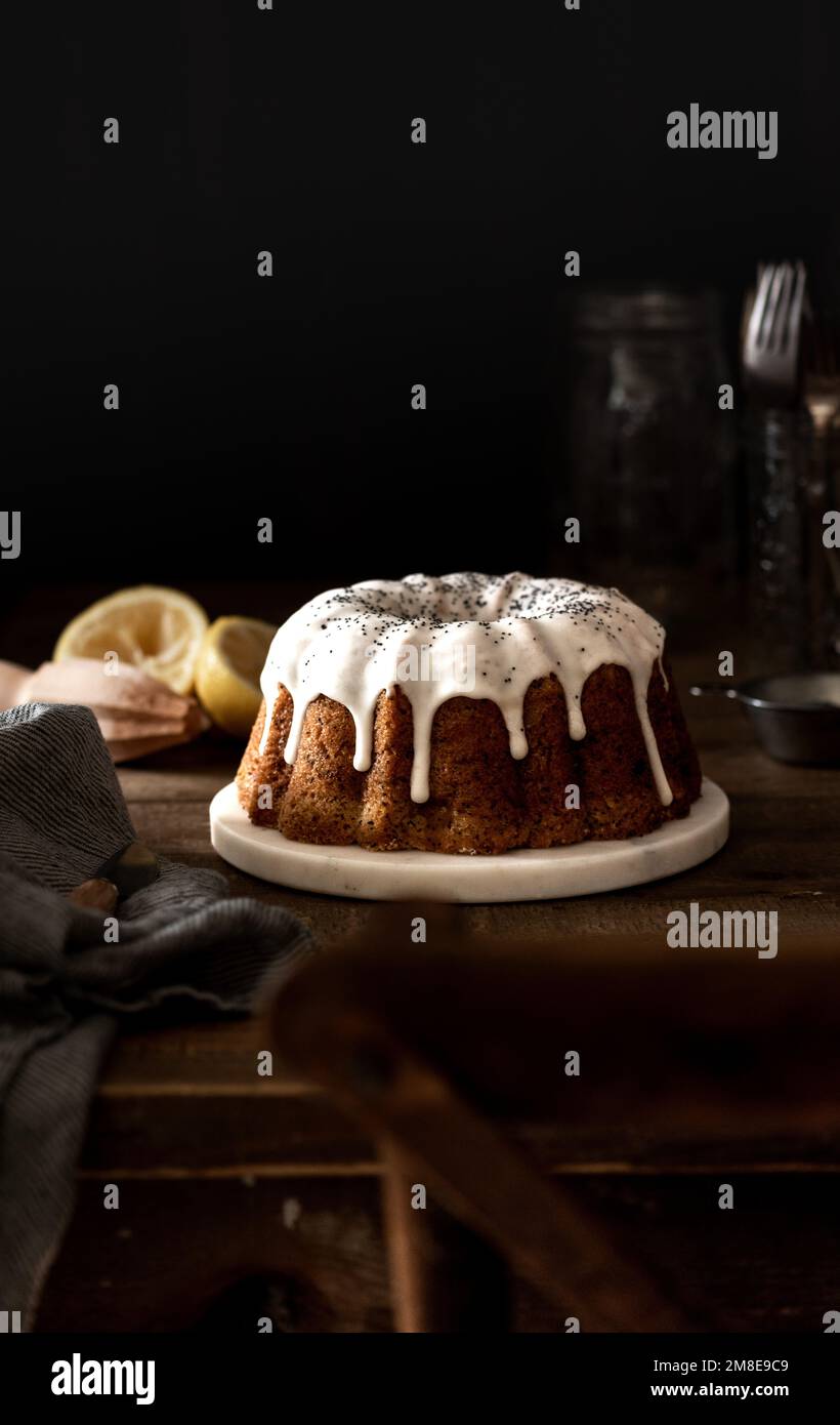 Table Scape with Lemon Drip Cake and Poppy Seeds Stock Photo