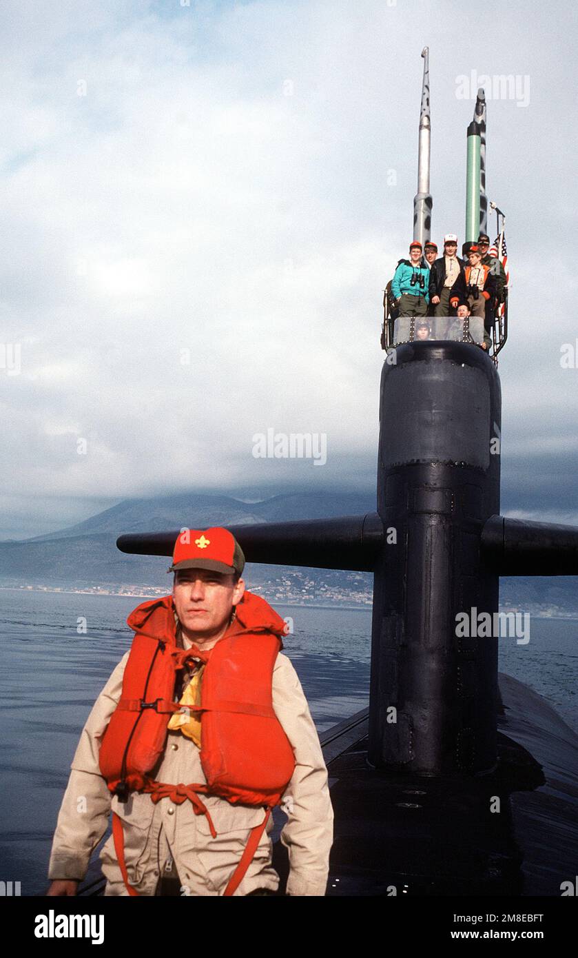 Owen C. Martin, scoutmaster of Boy Scout Troop 85, stands on the deck of the nuclear-powerd attack submarine USS PHILADELPHIA (SSN 690) as his scouts man the sail with CMDR Ryan, the ship's commanding officer. The troop has been aboard the vessel for a 36-hour stay arranged by Commander, Sixth Fleet. Base: Gaeta Country: Italy(ITA) Stock Photo