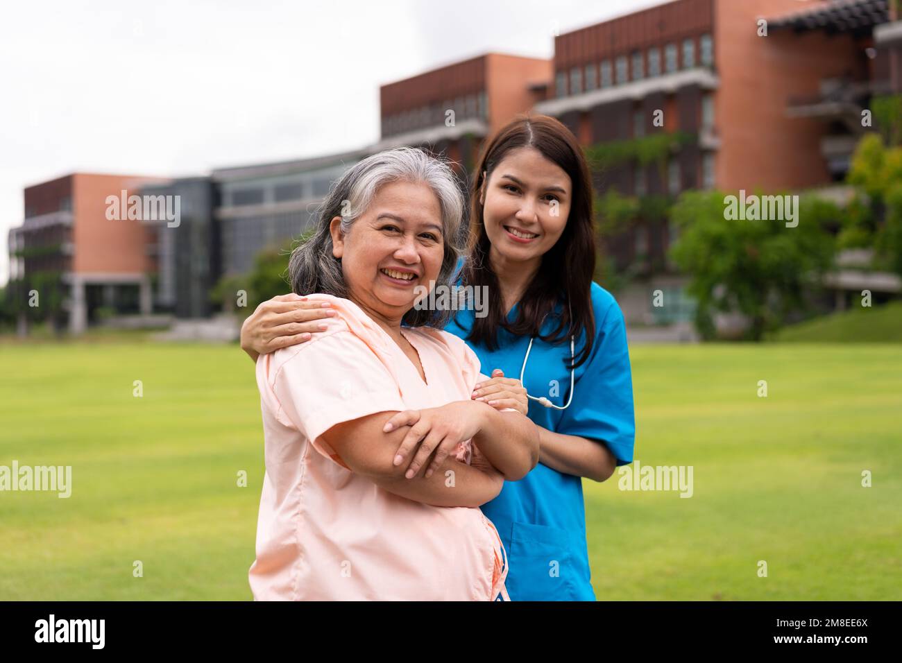 Asian careful caregiver or nurse hold the patient hand and encourage the patient in a garden. Concept of happy retirement with care from a caregiver a Stock Photo