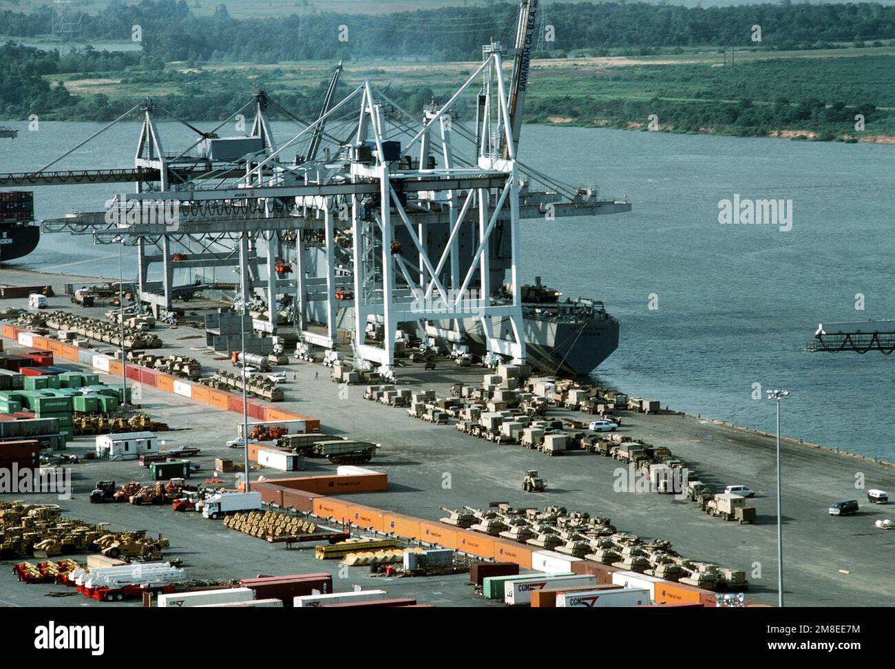 Equipment of the 24th Infantry Division lines the pier prior to loading aboard the rapid-response vehicle cargo ship USNS ALGOL (T-AKR-287). The cranes positioned beside the REGULUS will be used to move the equipment, which is being deployed to Saudi Arabia during Operation Desert Shield. Subject Operation/Series: DESERT SHIELD Base: Savannah State: Georgia (GA) Country: United States Of America (USA) Stock Photo