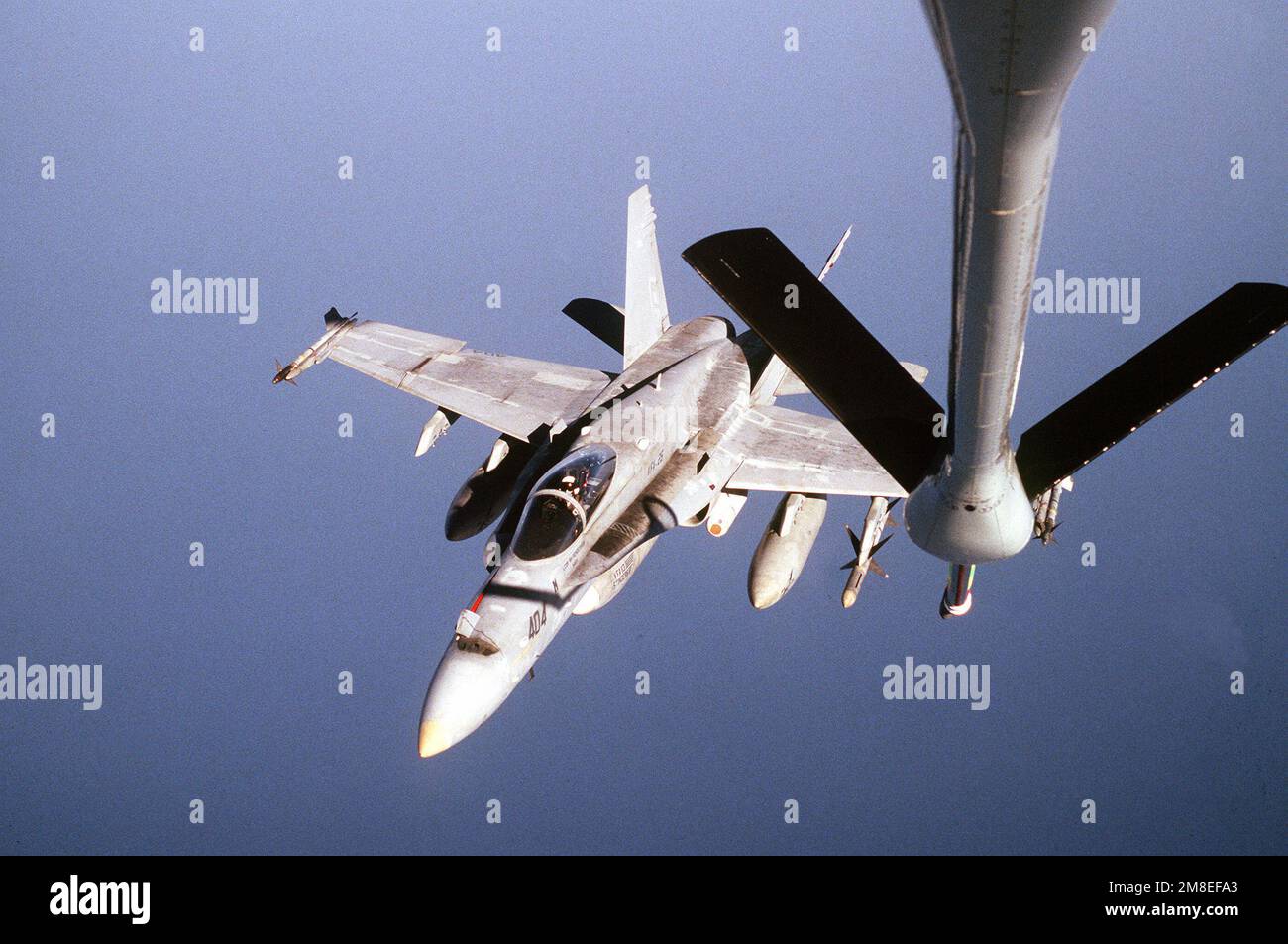 A Fighter Squadron 25 (VFA-25) F/A-18C Hornet aircraft flies beneath the refueling boom of an Air Force KC-135 Stratotanker aircraft off the eastern coast of Saudi Arabia during Operation Desert Shield. The aircraft is carrying an AIM-9 Sidewinder missile on each wing tip, an AIM-7 Sparrow missile on its outboard port side wing pylon and a borrowed external fuel tank under its fuselage. VFA-25 is based aboard the aircraft carrier USS INDEPENDENCE (CV-62). Subject Operation/Series: DESERT SHIELD Country: Unknown Stock Photo