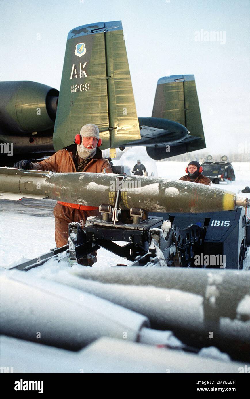 STAFF SGT. Joseph Labaska steadies a Mark 82 500-pound bomb on the arm of an MJ-1 weapons loader as he and the loader's driver, AIRMAN John Eskat, arm an A-10A Thunderbolt aircraft from the 343rd Tactical Fighter Wing during the joint readiness Exercise Arctic Warrior '91. Labaska and Eskat are members of the 343rd Aircraft Generation Squadron. Base: Eielson Air Force Base State: Alaska(AK) Country: United States Of America(USA) Stock Photo