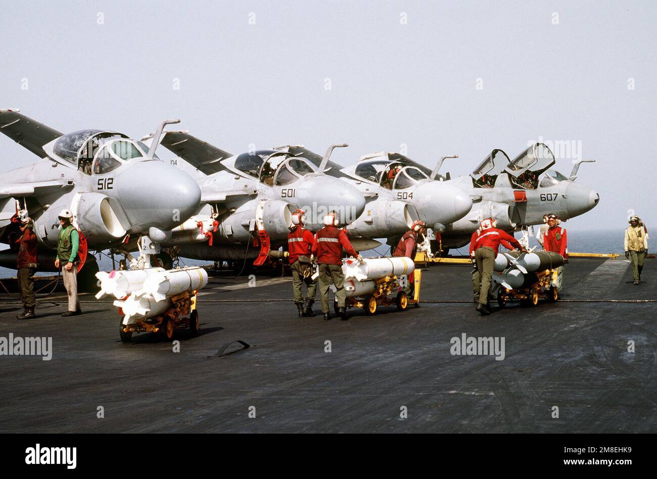 Aviation ordnancemen deliver two skids of Mark 20 Rockeye II cluster bombs, left and center, and a skid of general-purpose bombs to the area in front of three Attack Squadron 35 (VA-35) A-6E Intruder aircraft on the flight deck of the aircraft carrier USS SARATOGA (CV-60) during Operation Desert Storm. An EA-6B Prowler aircraft is at right. Subject Operation/Series: DESERT STORM Country: Red Sea Stock Photo