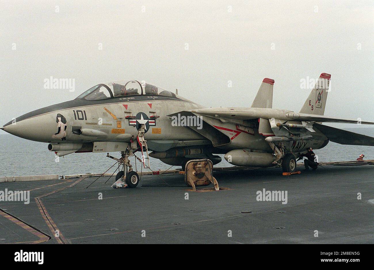 The F-14A Tomcat aircraft assigned to the commanding officer of Fighter Squadron 41 (VF-41) is readied for a mission on the flight deck of the nuclear-powered aircraft carrier USS THEODORE ROOSEVELT (CVN-71) during Operation Desert Storm. The 'Queen of Spades' painted on the nose of the aircraft is derived from VF-41's squadron name, the 'Black Aces.'. Subject Operation/Series: DESERT STORM Country: Unknown Stock Photo