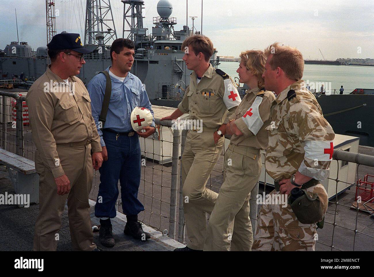 SENIOR CHIEF Hospital Corpsman W. C. Tutcher, left, and Hospital Corpsman 3rd Class Frank J. Chaves, second from left, compare notes with Dutch medical personnel on the deck of the Dutch fast combat support ship HNLMS ZUIDERKRUIS (A832) while the ship is in port during Operation Desert Storm. Tutcher and Chaves serve aboard the guided missile frigate USS MCINERNEY (FFG-8). Subject Operation/Series: DESERT STORM Country: Bahrain (BHR) Stock Photo