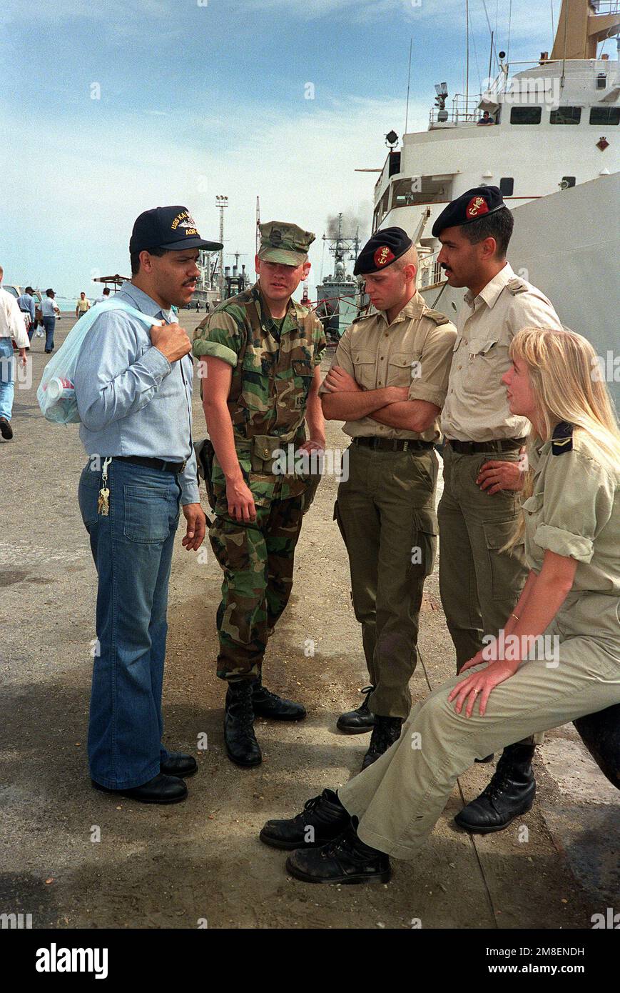 Postal Clerk 2nd Class Elliot Reyes, left, and Lance CPL. Mark A. Lamperi, second from left, talk with two Dutch marines and a Dutch sailor from the Dutch fast combat support ship HNLMS Zuiderkruis (A-832) while in port during Operation Desert Storm. Reyes serves aboard the replenishment oiler USS KALAMAZOO (AOR-6); Lamperi is a member of Fleet Anti-terrorist Security Team (FAST) Company, Pacific. Subject Operation/Series: DESERT STORM Country: Bahrain (BHR) Stock Photo