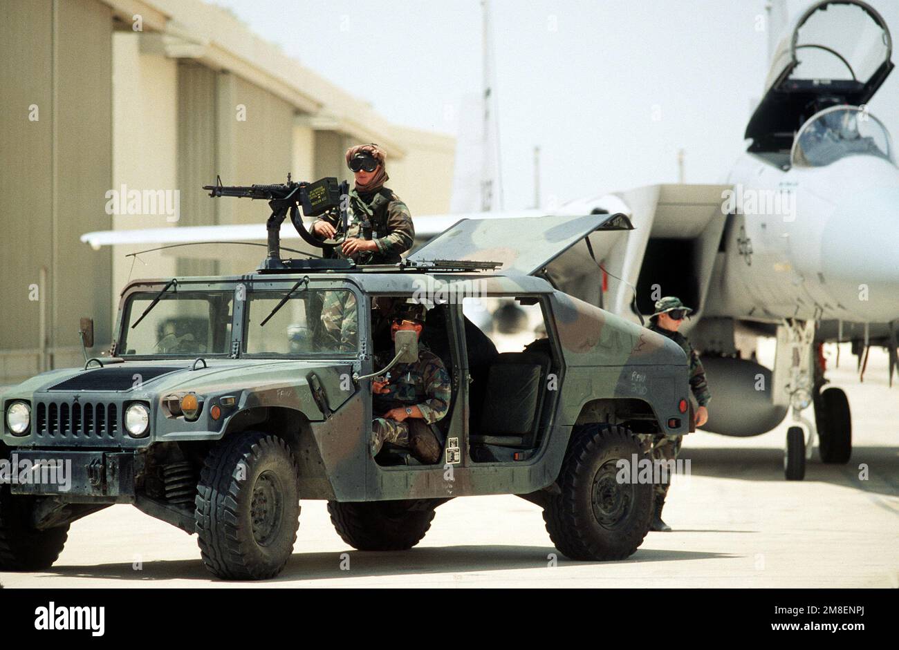 An Air Force security policeman mans a 7.62mm machine gun atop an M998 High-Mobility Multipurpose Wheeled Vehicle (HMMWV) as he stands guard near an F-15 Eagle aircraft during Operation Desert Shield. Subject Operation/Series: OPERATION DESERT SHIELD Country: Saudi Arabia (SAU) Stock Photo