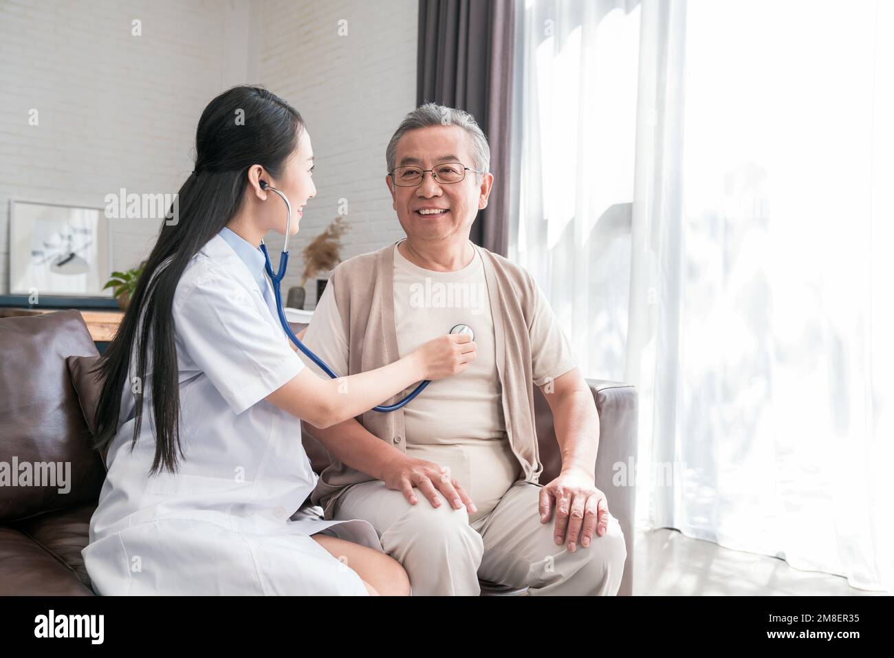 Young woman doctor to examine a older men Stock Photo