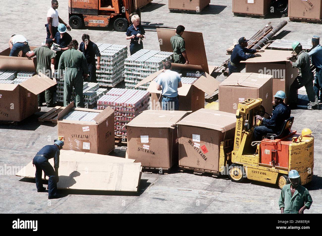 Dock workers and U.S. Navy supply personnel palletize cases of soft