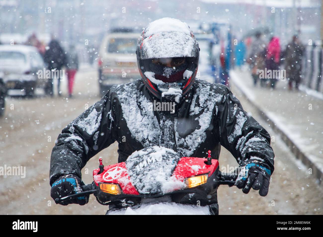 A scooty rider rides through a street amid ongoing heavy snowfall on the outskirts of Srinagar. At least two labourers killed on Thursday after an avalanche hits high-altitude area in central Kashmir's Sonamarg. Most parts of Kashmir received fresh snowfall that leading to the closure of Kashmir capital's main highway that connects disputed region with the rest of India. Meanwhile airport authorities suspended all flight operations till further notice due to continuous snowfall and low visibility. (Photo by Faisal Bashir/SOPA Images/Sipa USA) Stock Photo