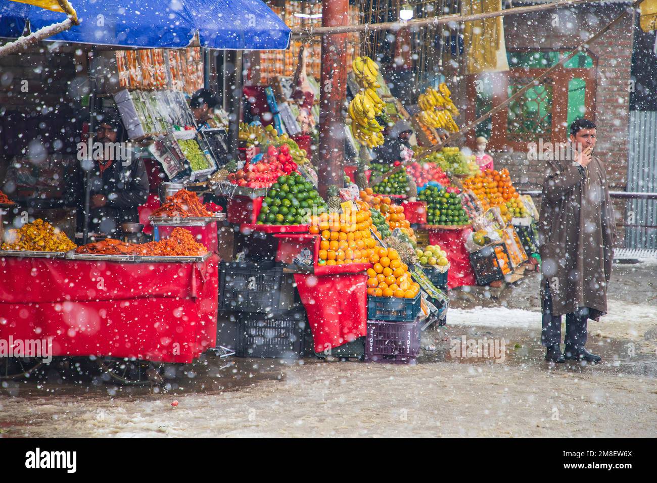 A fruit vendor waiting for customers amid ongoing heavy snowfall on the outskirts of Srinagar. At least two labourers killed on Thursday after an avalanche hits high-altitude area in central Kashmir's Sonamarg. Most parts of Kashmir received fresh snowfall that leading to the closure of Kashmir capital's main highway that connects disputed region with the rest of India. Meanwhile airport authorities suspended all flight operations till further notice due to continuous snowfall and low visibility. (Photo by Faisal Bashir/SOPA Images/Sipa USA) Stock Photo