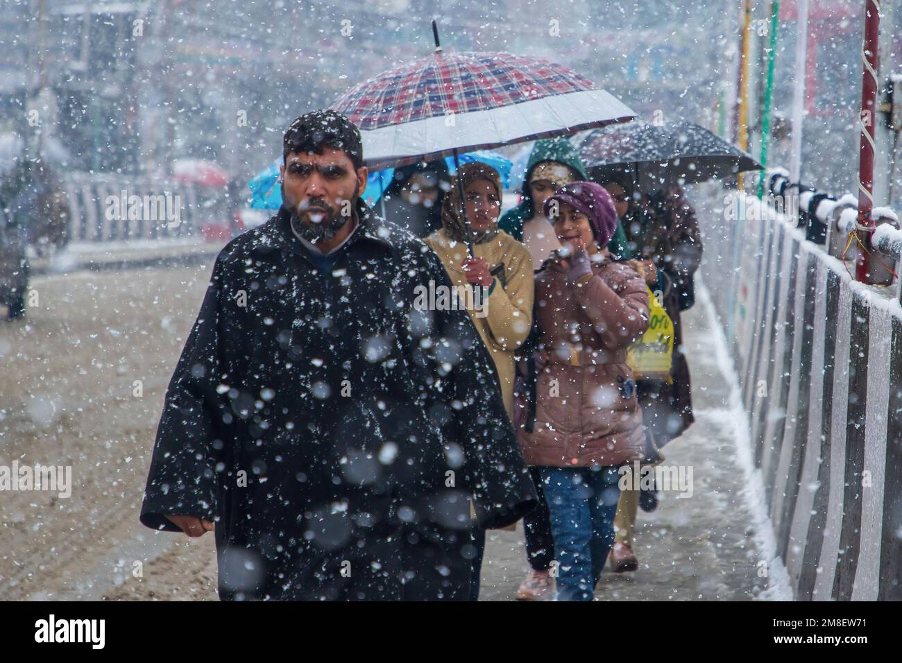 People walk through a street amid ongoing heavy snowfall on the outskirts of Srinagar. At least two labourers killed on Thursday after an avalanche hits high-altitude area in central Kashmir's Sonamarg. Most parts of Kashmir received fresh snowfall that leading to the closure of Kashmir capital's main highway that connects disputed region with the rest of India. Meanwhile airport authorities suspended all flight operations till further notice due to continuous snowfall and low visibility. (Photo by Faisal Bashir/SOPA Images/Sipa USA) Stock Photo