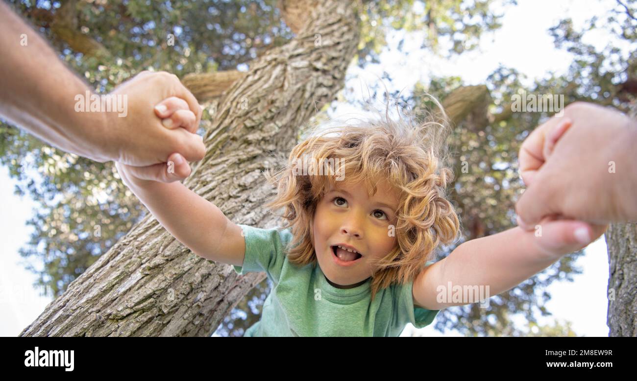 Fathers hand. Spring banner. Father helping son to climbing. Parent holds the hand of child. Stock Photo