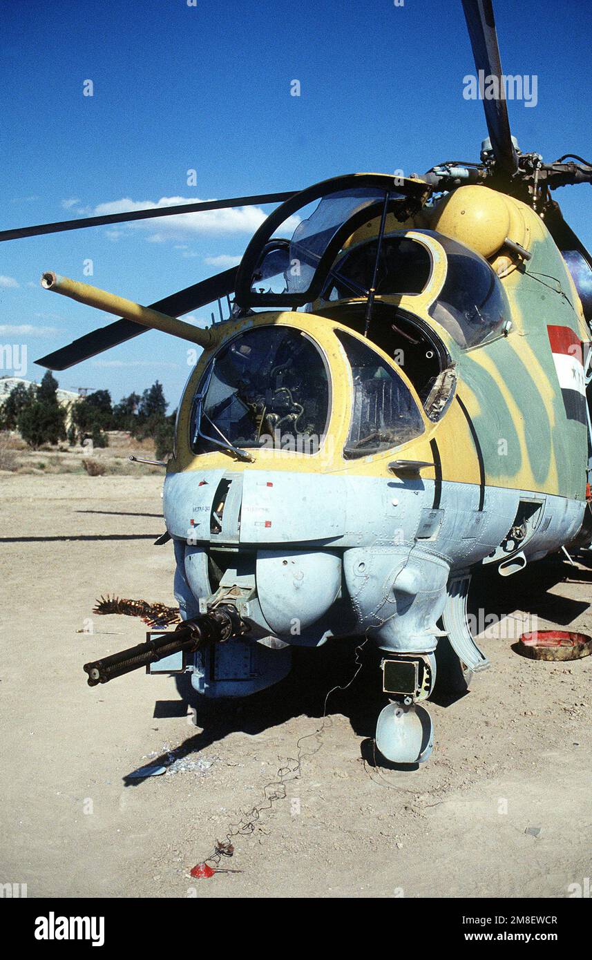 An Iraqi MIL Mi-24 Hind-D assault helicopter abandoned during Operation Desert Storm. A belt of ammunition for the chin-mounted, remotely-controlled, four-barrel 12.7mm Gatling-type machine gun is on the ground to the left.. Subject Operation/Series: DESERT STORM Country: Iraq(IRQ) Stock Photo