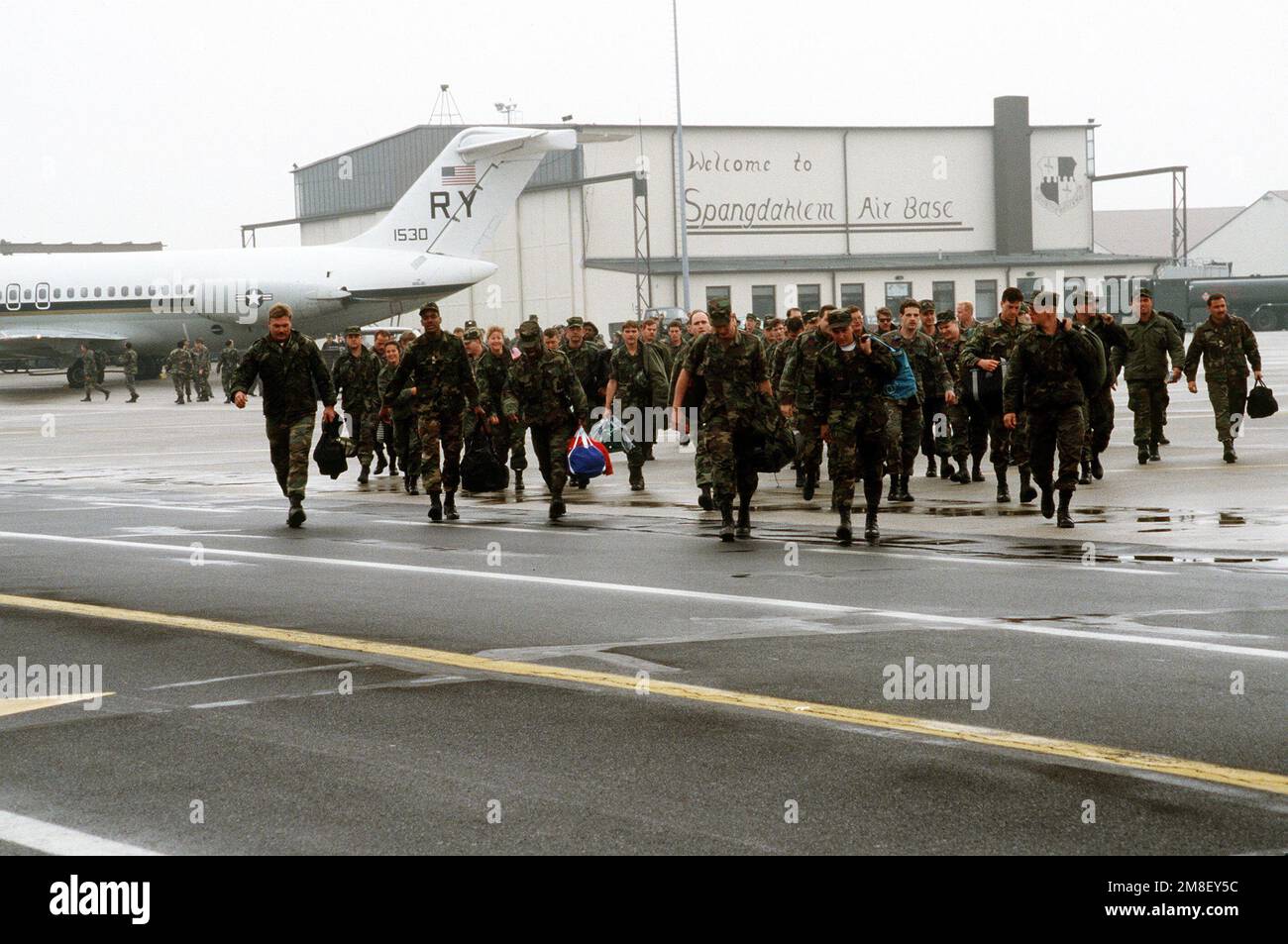 A group of military personnel walk across the flight line to greet their families and friends after returning from Incirlik Air Base, Turkey, where they served in support of Operation Desert Storm. Behind them is a C-9B Skytrain II transport aircraft from Fleet Logistics Support Squadron 59 (VR-59).. Subject Operation/Series: DESERT STORM Base: Spangdahlem Air Base State: Rheinland-Pfalz Country: Deutschland / Germany(DEU) Stock Photo