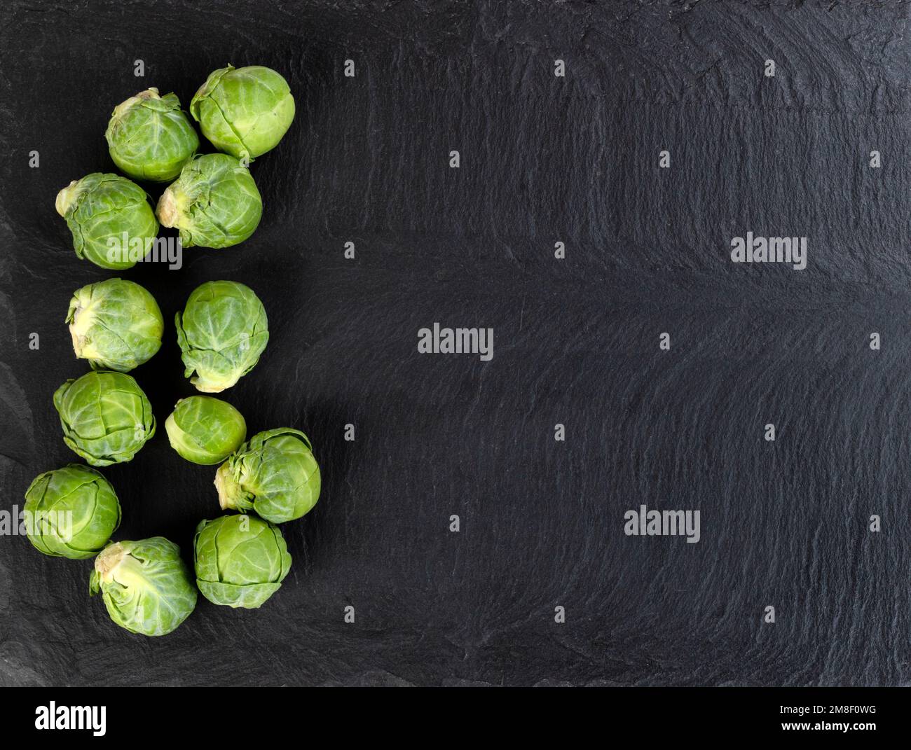Fresh raw organic brussel sprouts on black stone background in flat lay view Stock Photo