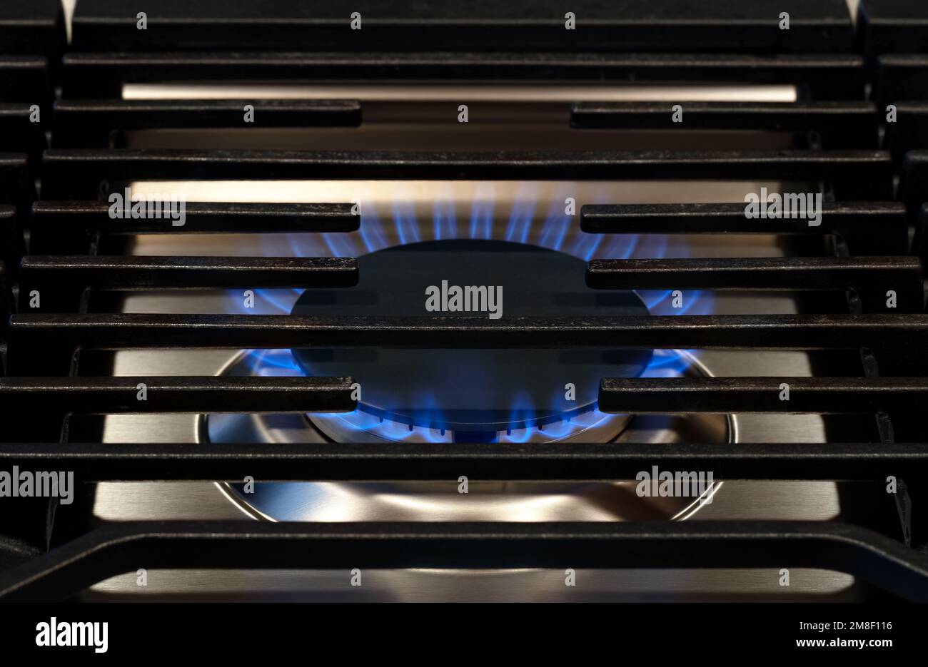 Modern Kitchen stove top cook. Gas flame close up on a natural gas stove range burner with metal grill Stock Photo
