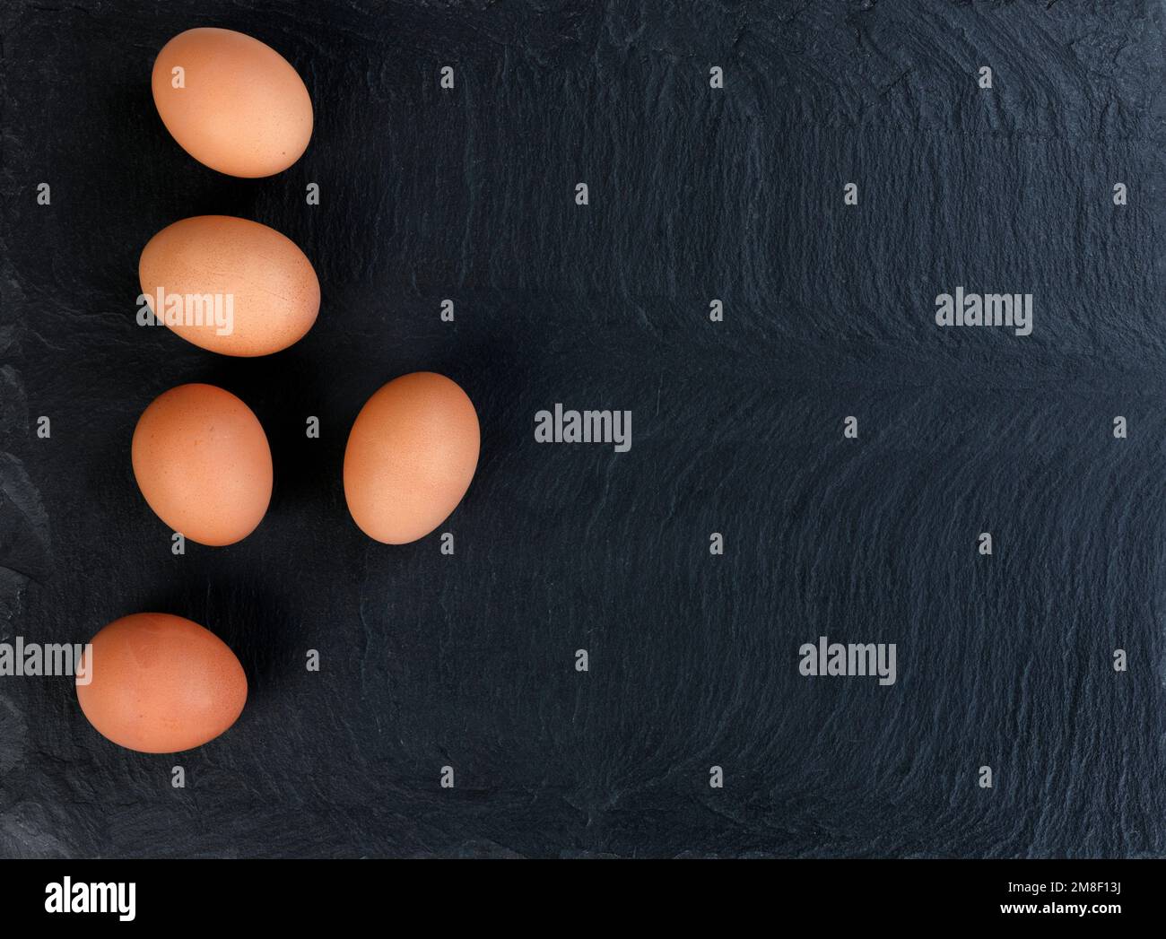 Organic brown chicken eggs on black stone background in flat lay view Stock Photo