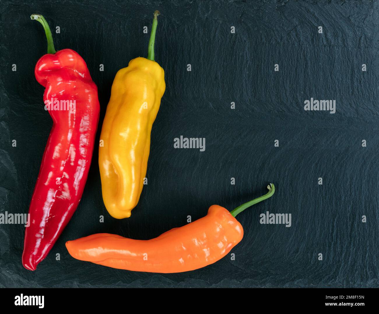 Fresh Sweet peppers on black stone background in flat lay view Stock Photo