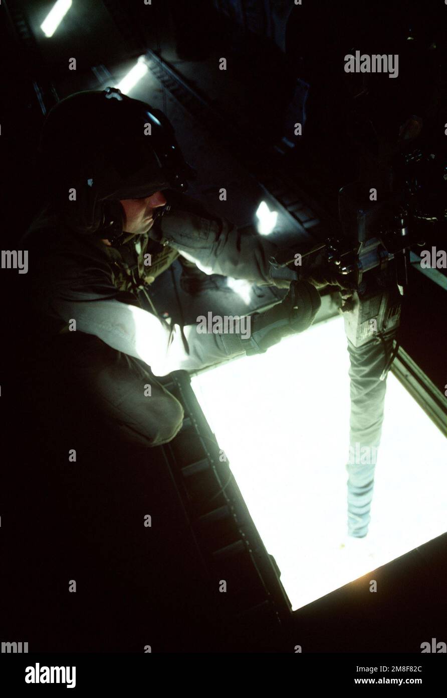 A Marine crew chief controls the hoisting of fuel bladders from inside