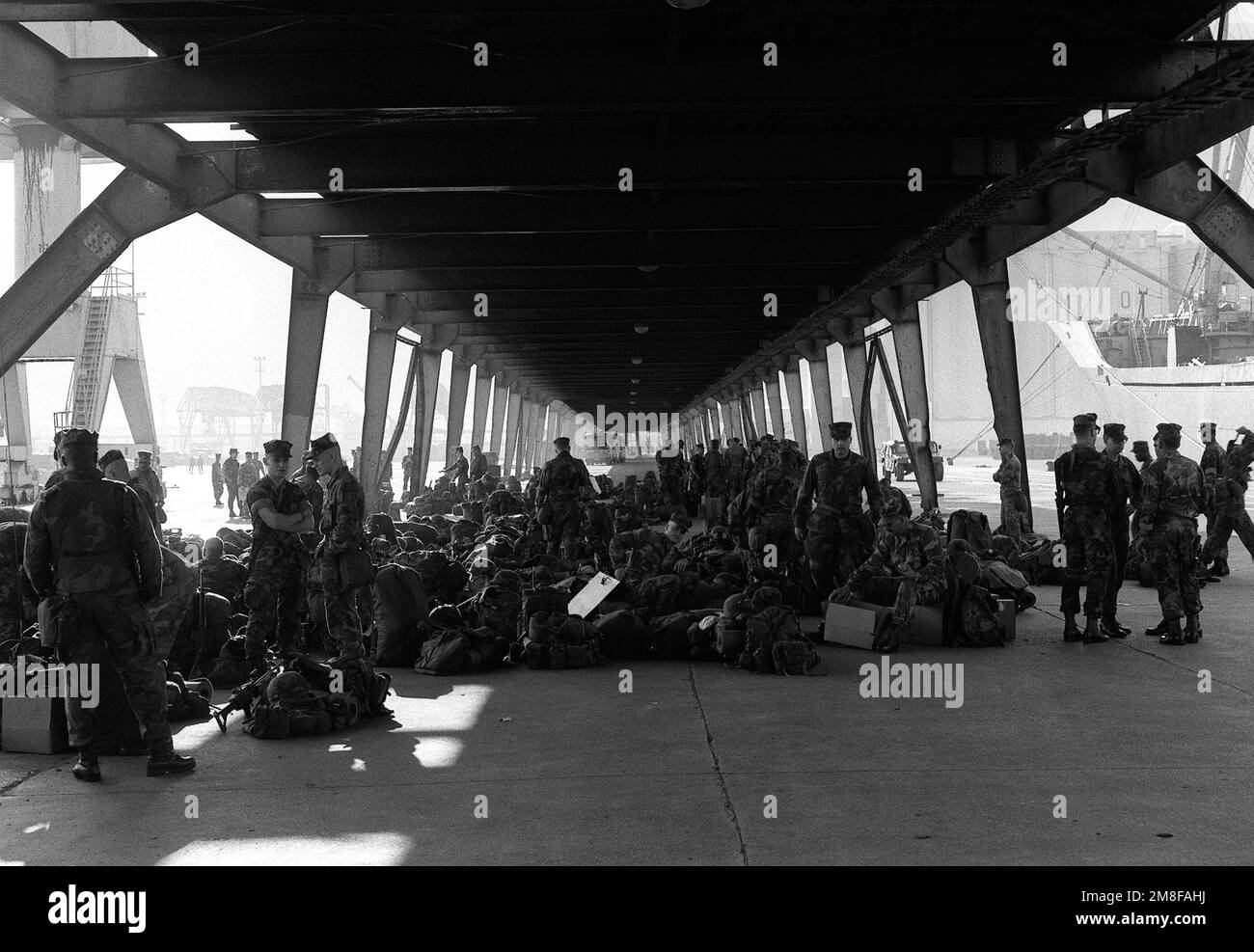 Marines sit beneath a structure on the pier as they await transportation to outlying camps during Operation Provide Comfort, an Allied effort to aid Kurdish refugees who fled from the forces of Saddam Hussein in northern Iraq. Subject Operation/Series: PROVIDE COMFORT Base: Iskenderum Country: Turkey (TUR) Stock Photo