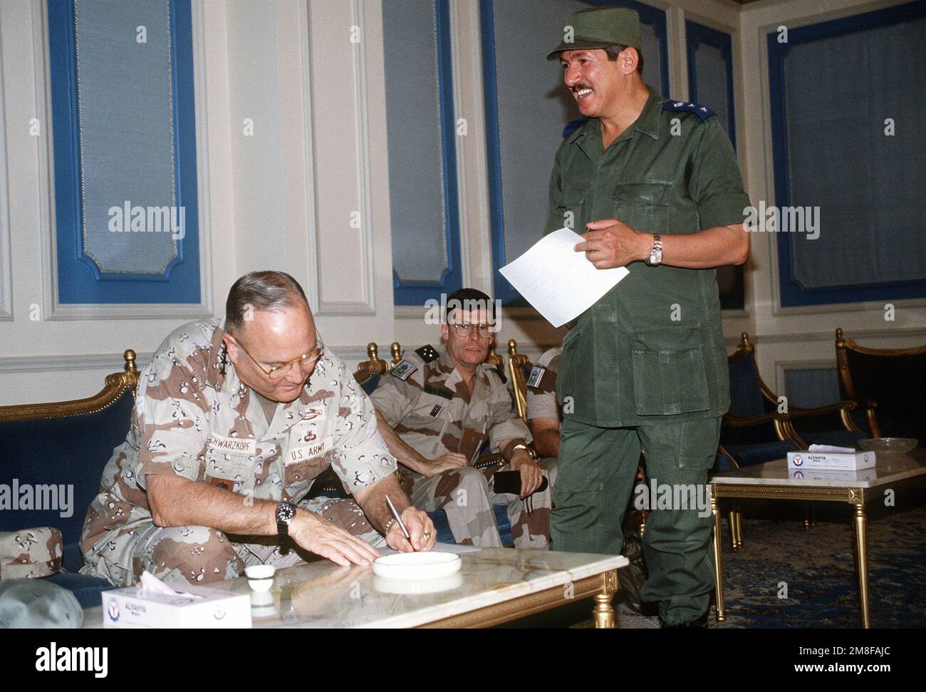 GEN. Norman Schwarzkopf, commander-in-chief, U.S. Central Command, pauses to sign an autograph for a Saudi officer while having tea with LT. GEN. Khalid Bin Sultan Bin Abdul Aziz, commander of Arab forces. Schwarzkopf is visiting coalition forces stationed at Riyadh Air Base in the aftermath of Operation Desert Storm. Subject Operation/Series: DESERT STORM Country: Saudi Arabia(SAU) Stock Photo