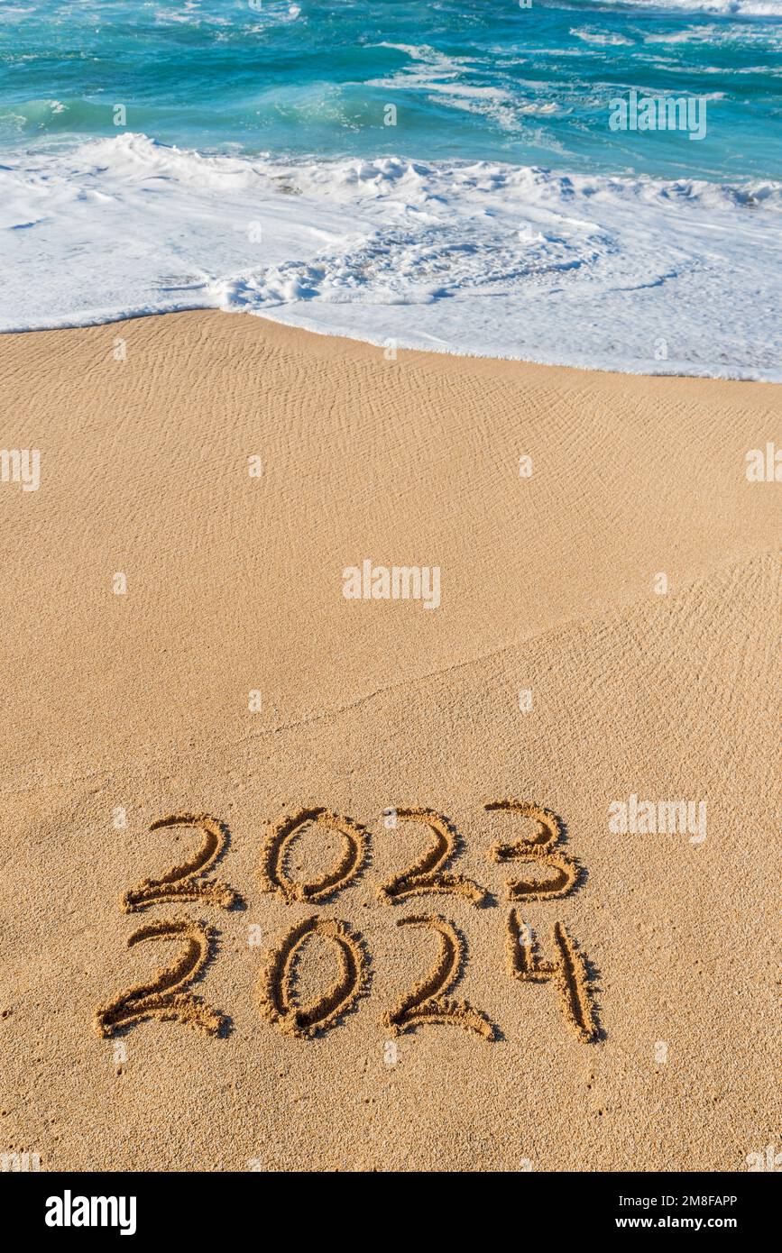 2023 2024 written in the sand with wave washing up New Year concept