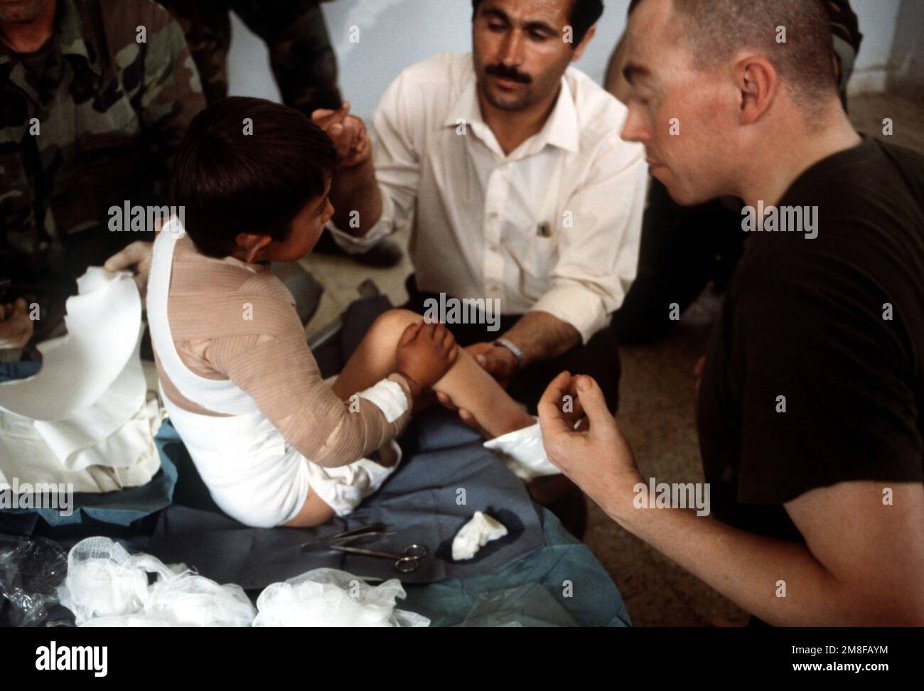 Military personnel provide medical assistance to a small boy at one of the refugee camps set up outside of Zakhu as part of Operation Provide Comfort, an Allied effort to aid Kurdish refugees who fled from the forces of Saddam Hussein in northern Iraq. Subject Operation/Series: PROVIDE COMFORT Country: Iraq (IRQ) Stock Photo