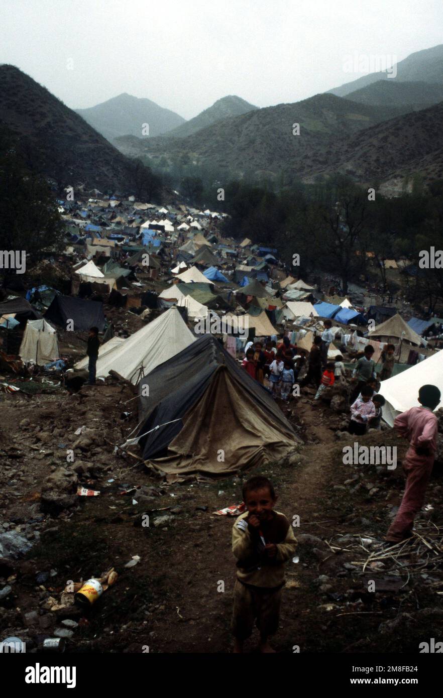 A little Kurdish boy smiles for the camera as other children gather in ...