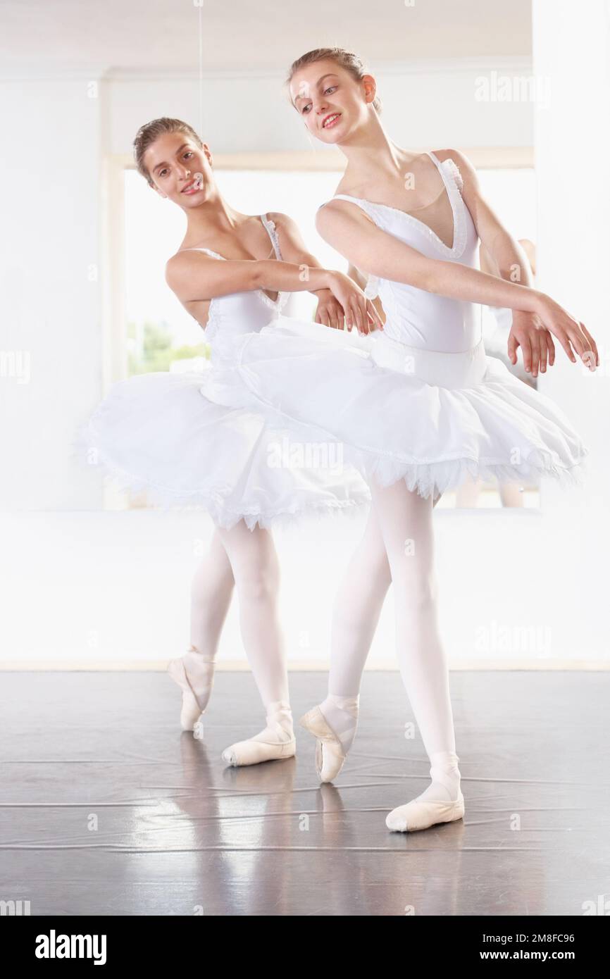 Mirroring each others movements. Full length shot of two ballerinas