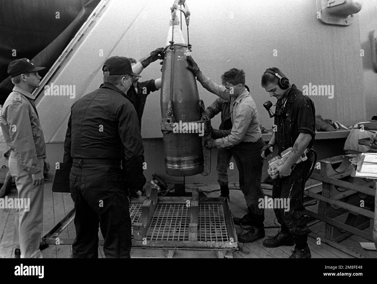 crewmen-guide-a-16-inch-projectile-as-it-is-lowered-to-a-pallet-on-the