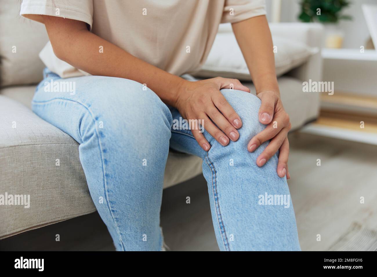 Woman sitting on the couch at home leg and foot pain, sprain and muscle