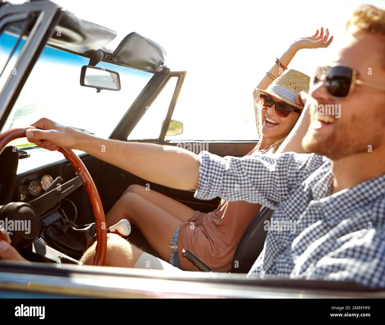 Car road trip, travel and laughing couple on bonding holiday adventure, transportation journey or fun summer vacation. Love flare, convertible Stock Photo