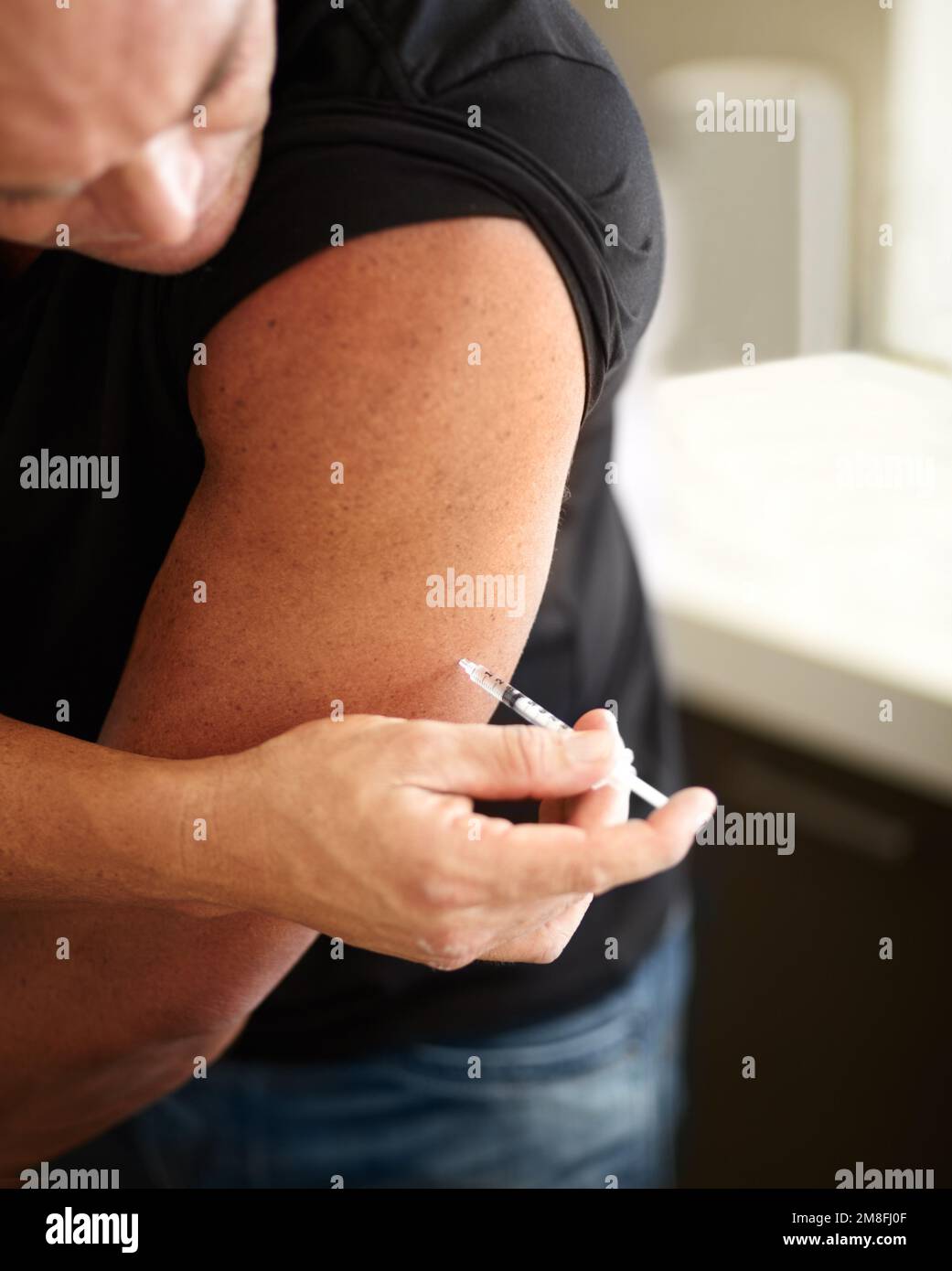 Using performance enhancing drugs. Closeup of a muscular man injecting himself with steroids. Stock Photo