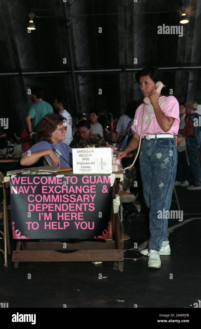 A woman makes a telephone call from a desk in a temporary evacuation center during Operation Fiery Vigil. The center was set up to process military dependents who were evacuated from the Philippines after volcanic ash from the eruption of Mount Pinatubo disrupted operations at Clark Air Base and Naval Station, Subic Bay.. Subject Operation/Series: FIERY VIGIL Base: Andersen Air Base State: Guam(GU) Country: United States Of America(USA) Stock Photo