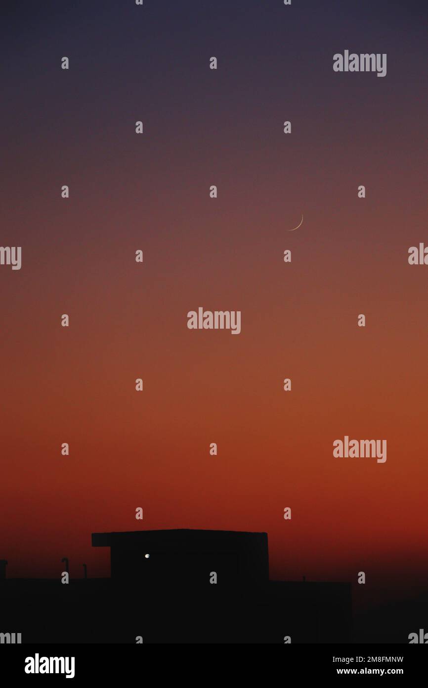 A silhouette houses in a distance under orange evening sky, vertical ...