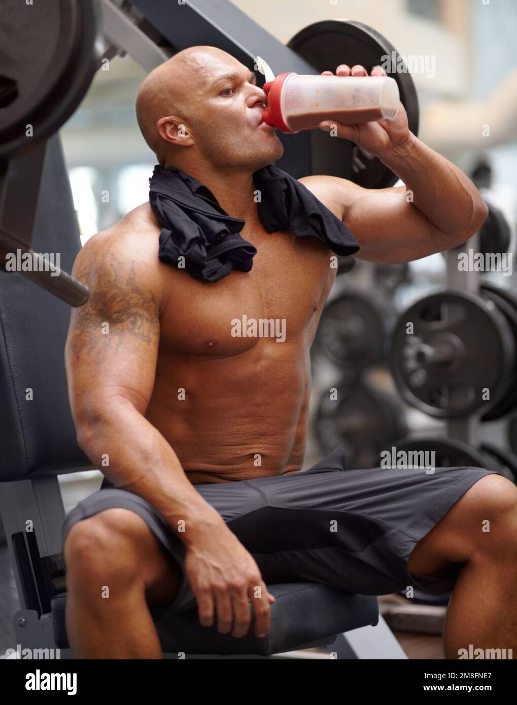 Keeping his energy levels up. a male bodybuilder drinking a protein