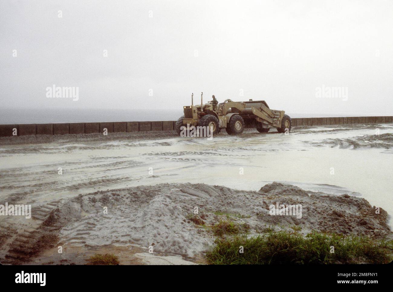 A Seabee drives a motorized earthmoving scraper along a road being ...