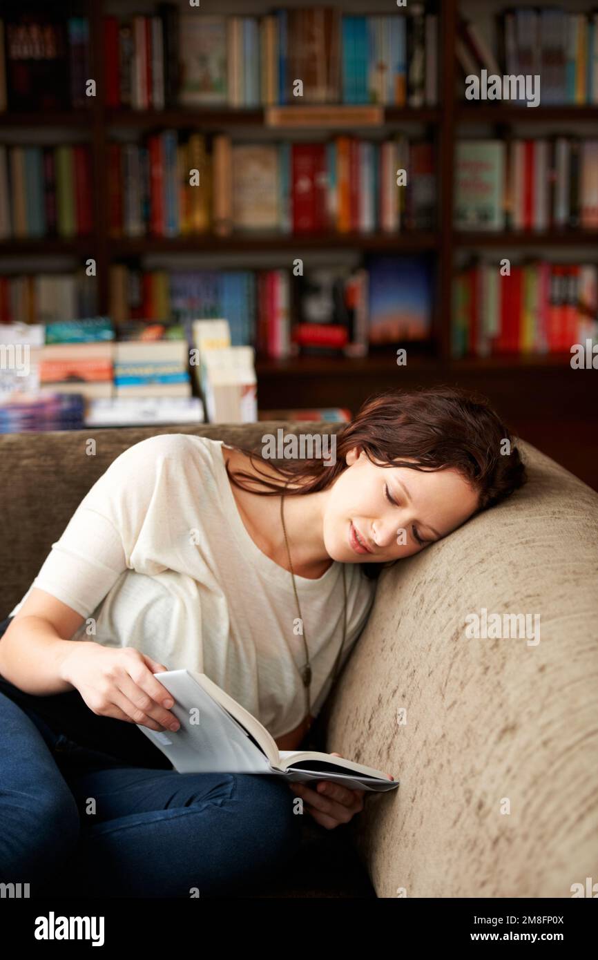 Spirited away with words. An attractive young woman relaxing on a sofa