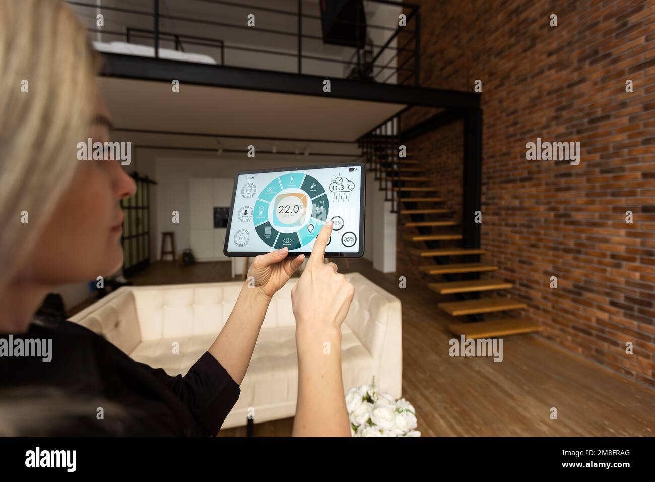 Woman controlling smart home devices using a digital tablet with ...